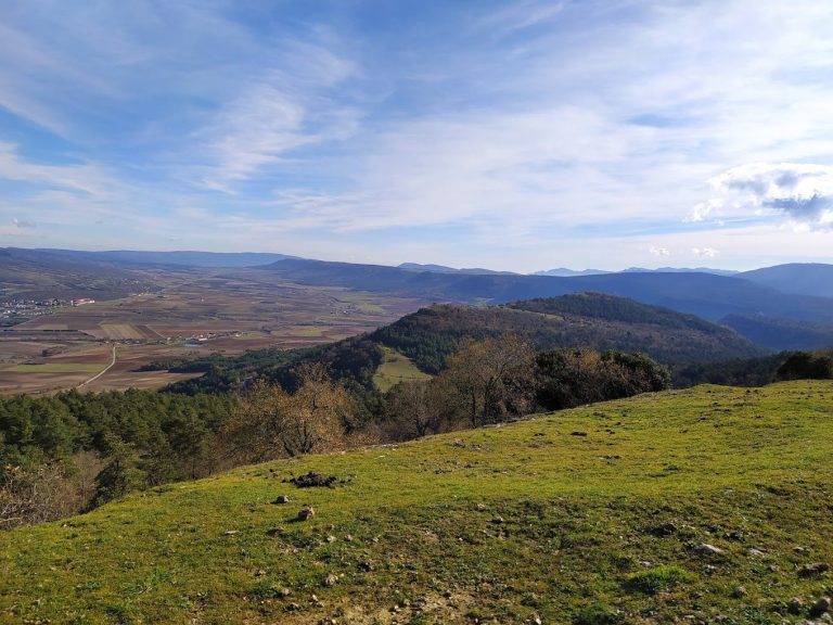 Vista panorámica de colinas y valles bajo un cielo azul con algunas nubes.